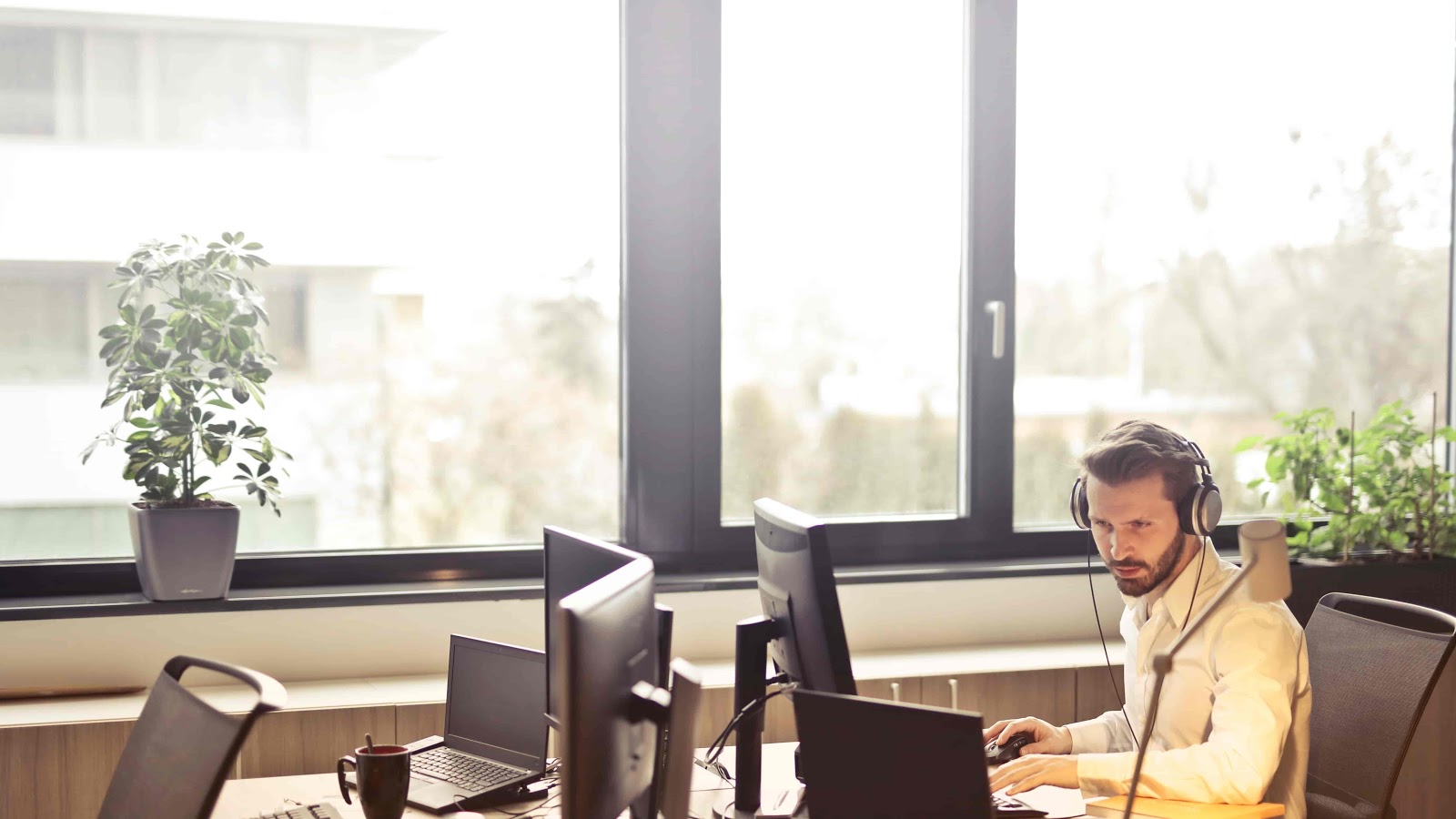 man working at a desk next to large window