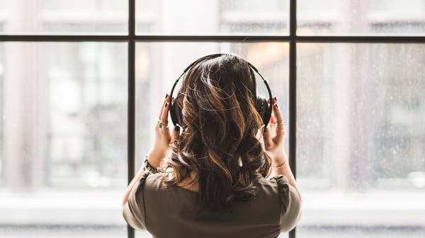 woman wearing headphone in front of a window